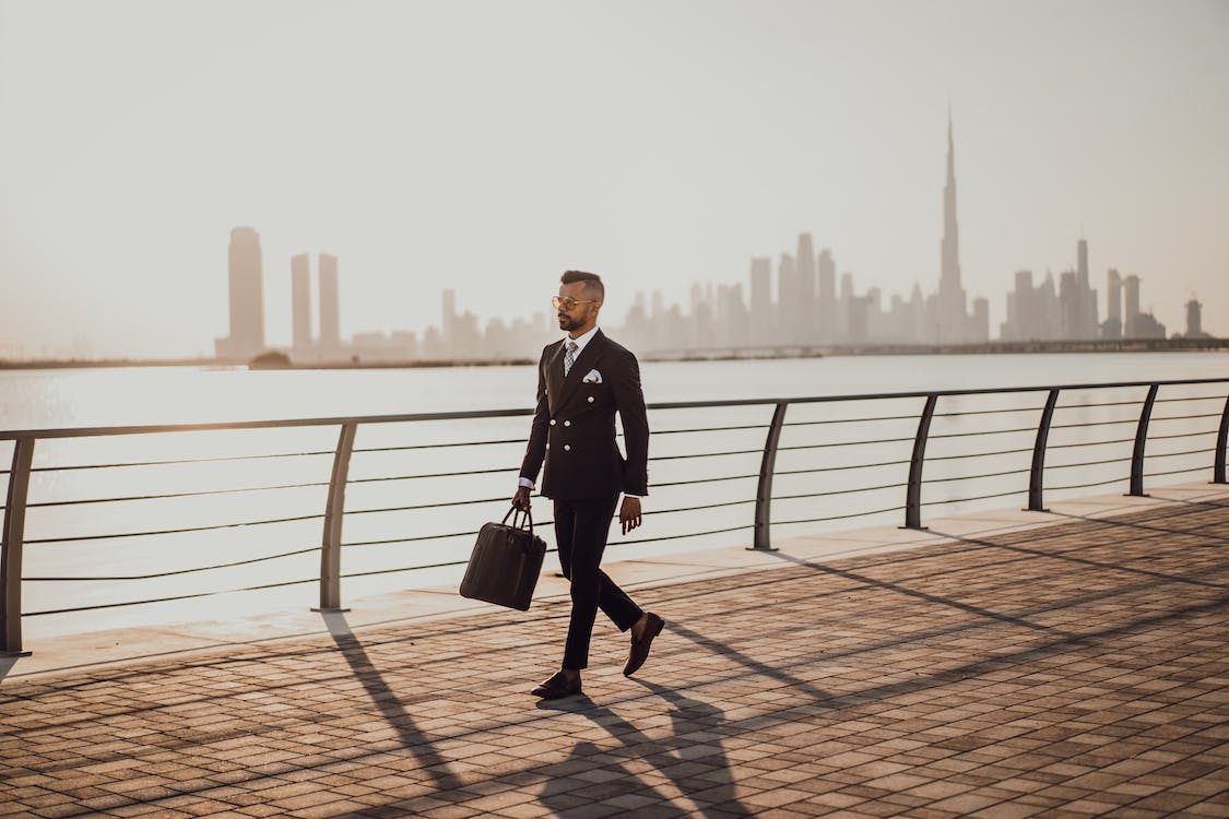 A stock photo of a businessman with briefcase walking along the water in Dubai.