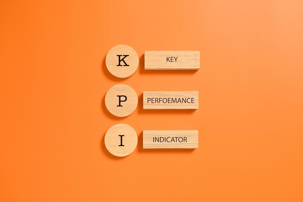 Orange back ground with wooden tiles spelling out KPI which is a vital part of a sales strategy